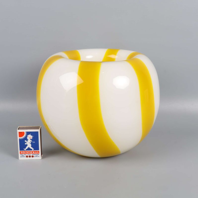 Vas med gula ränder jämte tändsticksask för storleksreferens