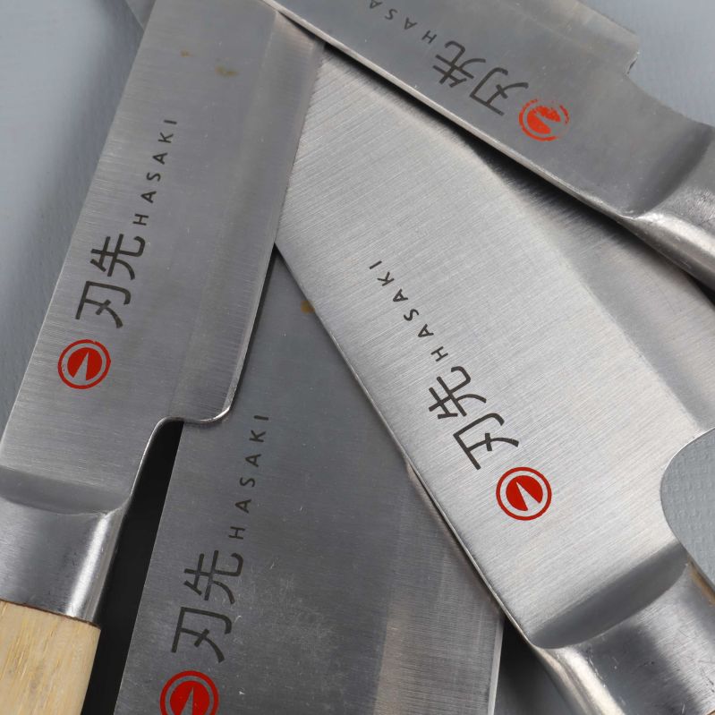 Närbild på knivblad med Hasaki-logga och japanska tecken