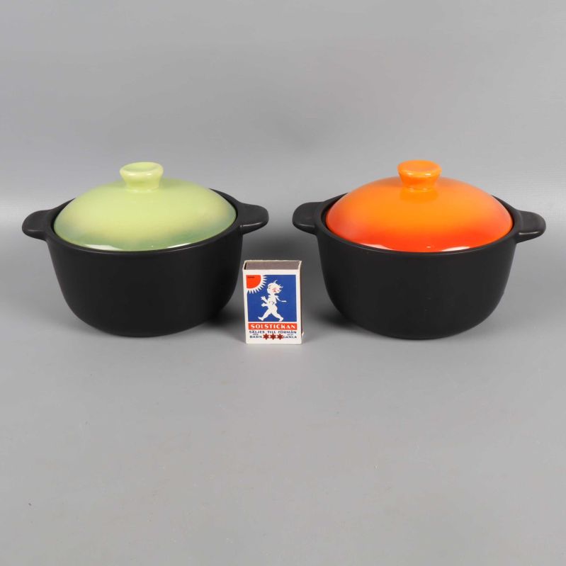 Grytor med grönt och orange lock bredvid tändsticksask