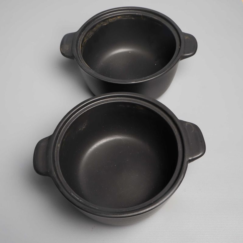 Två svarta grytor utan lock med slitna kanter synliga