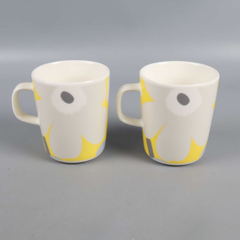 Två muggar med handtag och blommönster i vitt, gult och grått