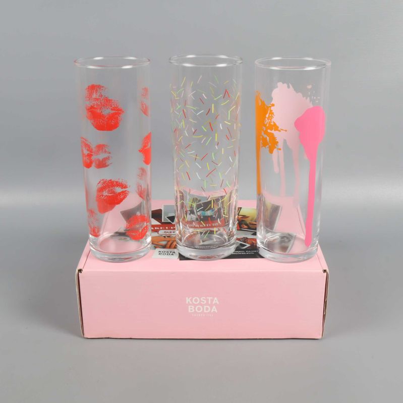 Höga glas med tryck av läppar, konfetti och färgstänk ovanpå rosa kartong