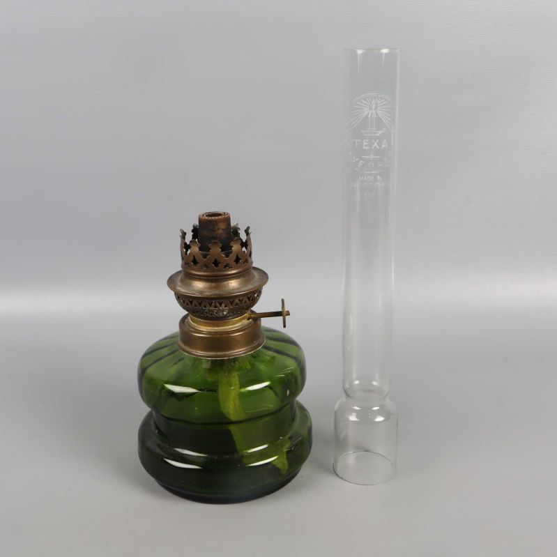 Omontad fotogenlampa med glasrör bredvid grön bas