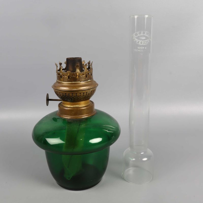 Separat bild på grön glaskupa med mässingsdel och avmonterad glascylinder bredvid