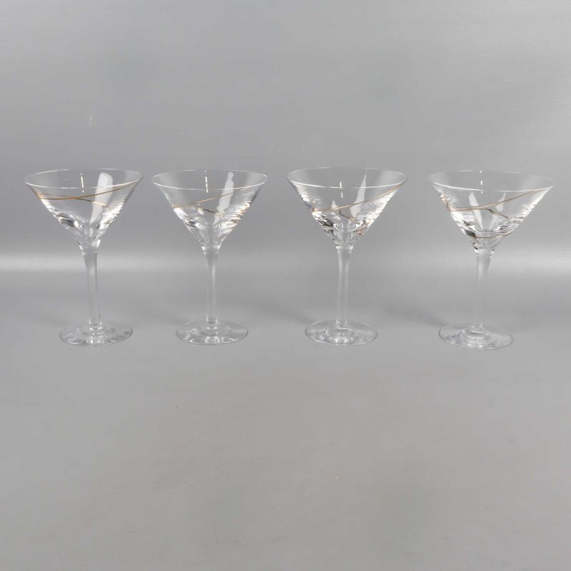 Fyra cocktailglas på rad på grå yta