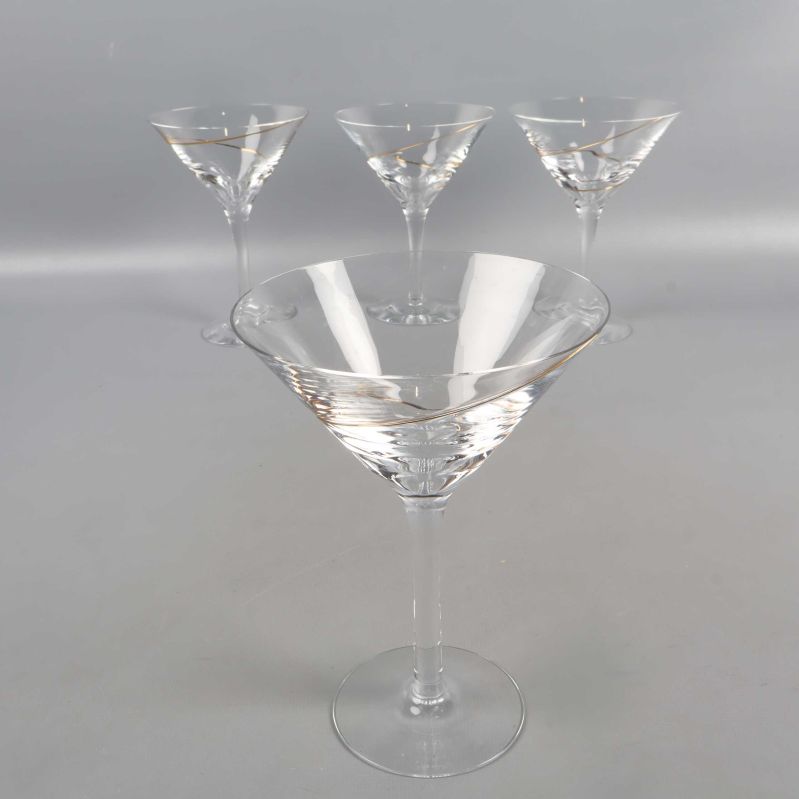 Fyra cocktailglas med spiraldekor i guld på grå bakgrund