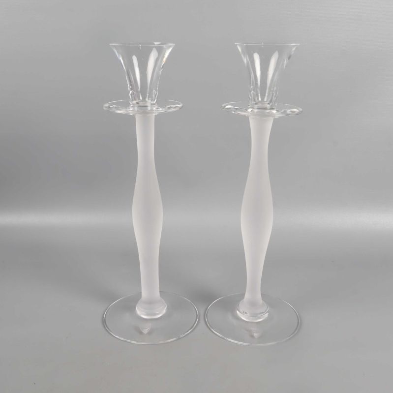 Två ljusstakar i glas stående bredvid varandra mot ljus bakgrund