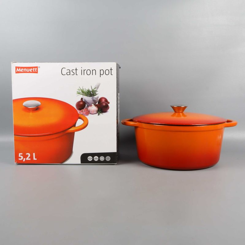 Gjutjärnsgryta med orange lock bredvid originalförpackning