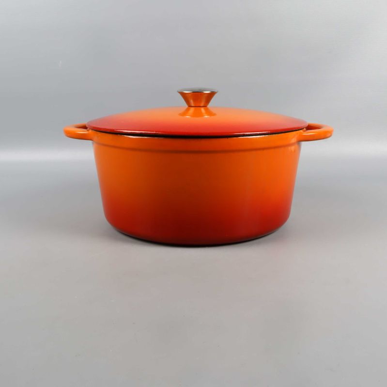 Orange gjutjärnsgryta fotograferad rakt framifrån med lock på