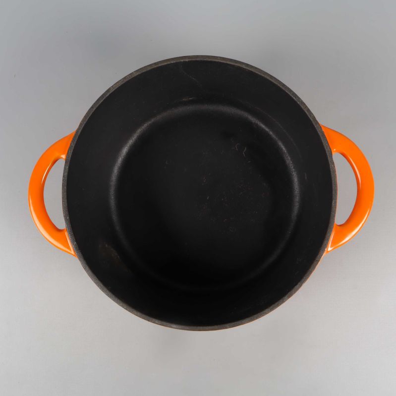 Insidan av gjutjärnsgrytan med svarta stekyta och orange handtag