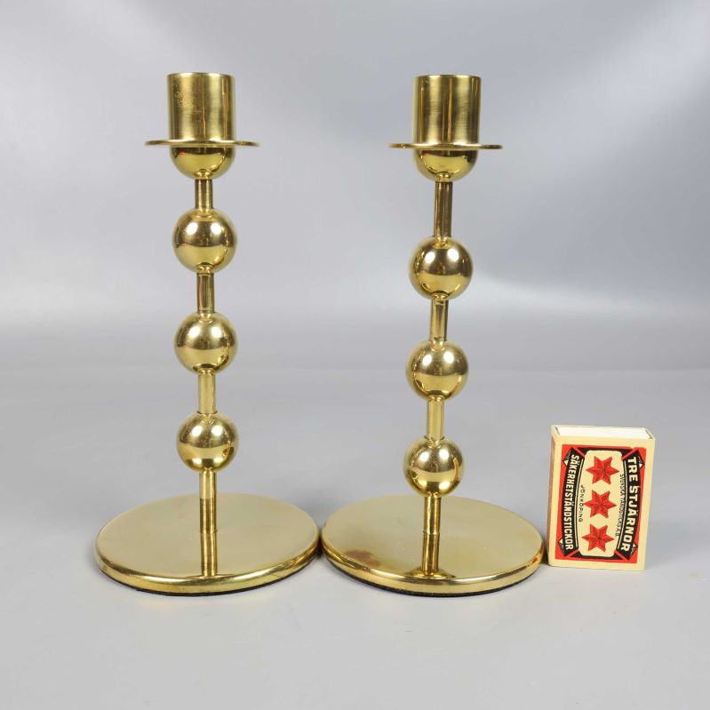 Två mässingsljusstakar står bredvid en tändsticksask