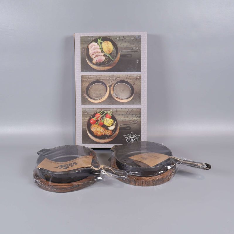 Två gjutjärnspannor med träunderlägg och förpackning bakom