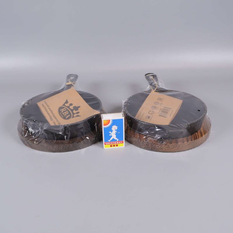 Gjutjärnspannor med träunderlägg bredvid tändsticksask