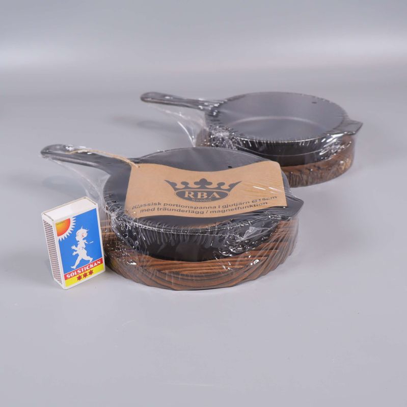 Två portionspannor med träunderlägg jämte tändsticksask