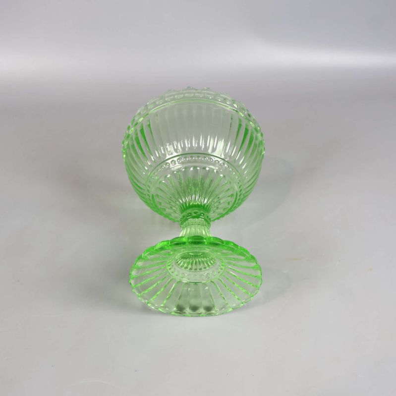 Grön glasskål på fot liggande på sidan