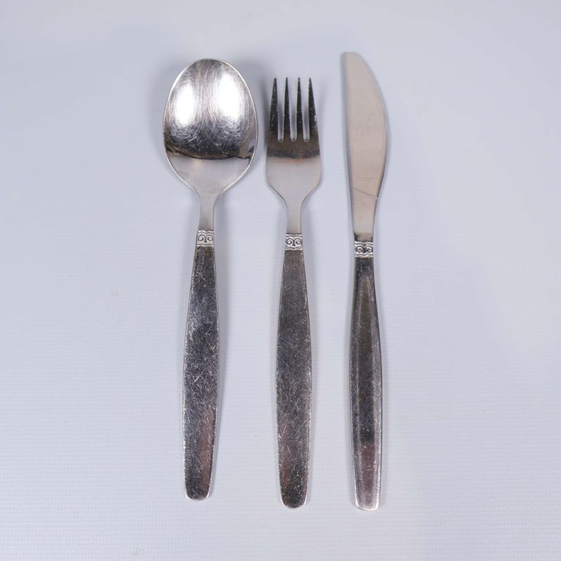 Närbild på en sked, gaffel och kniv med diskret dekormönster