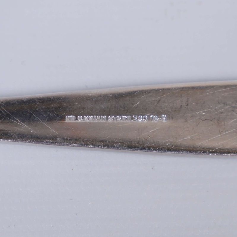 Stämpel med texten 'NILSJOHAN ROSTFRITT STÅL SWEDEN' på bestick