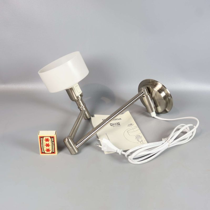 Vägglampa placerad bredvid tändsticksask och monteringsanvisning