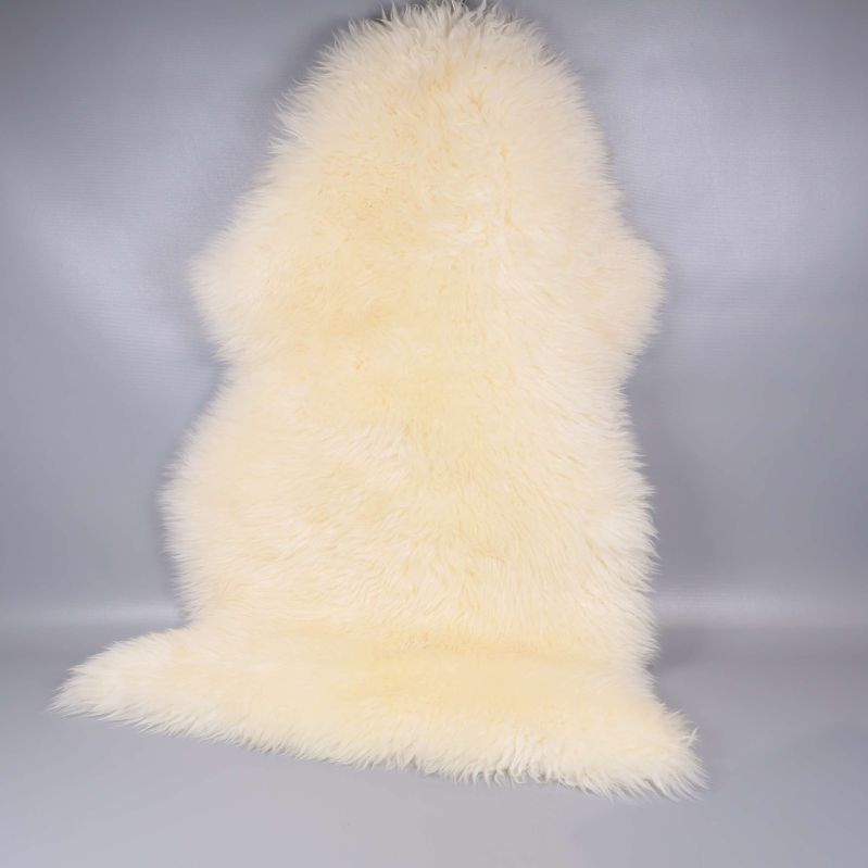 Långhårigt vitt fårskinn visas framifrån mot grå bakgrund