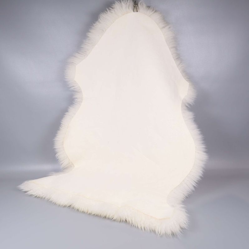 Baksidan av vitt långhårigt fårskinn mot grå bakgrund