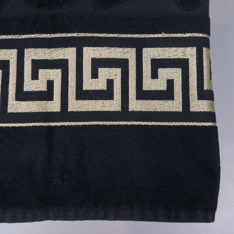 Närbild på guldig grekisk bård mot svart tyg