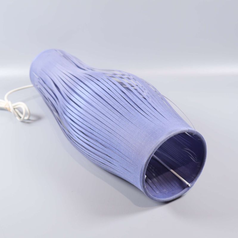 Taklampa i blå nyans liggande med synliga band