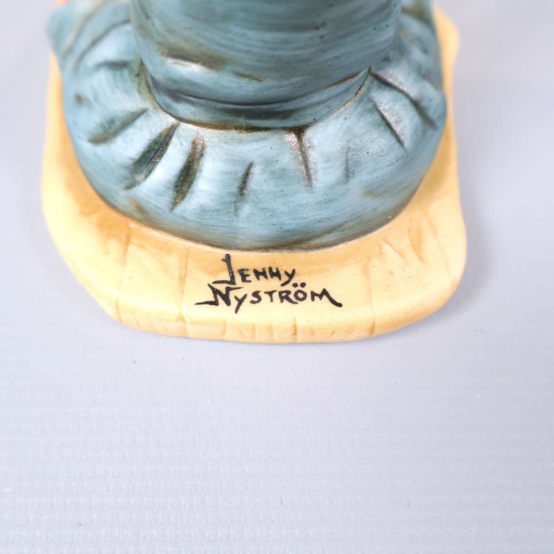 Undersida av figuren med blå stämpel och text