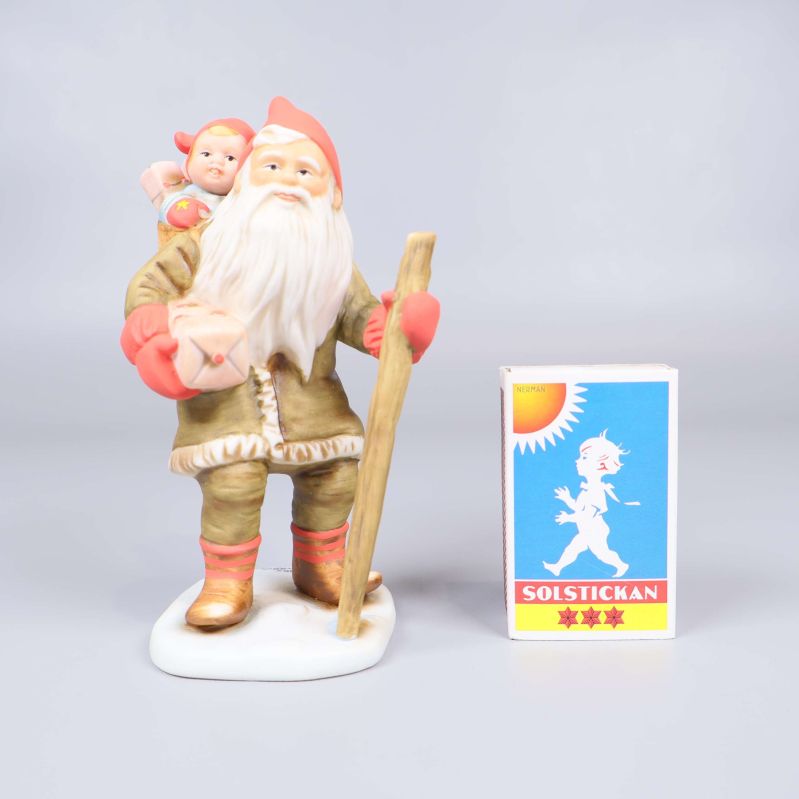 Tomtefigur stående bredvid tändsticksask som storleksreferens