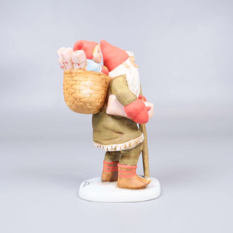 Tomtefigur sedd snett bakifrån med tydlig korg och barn