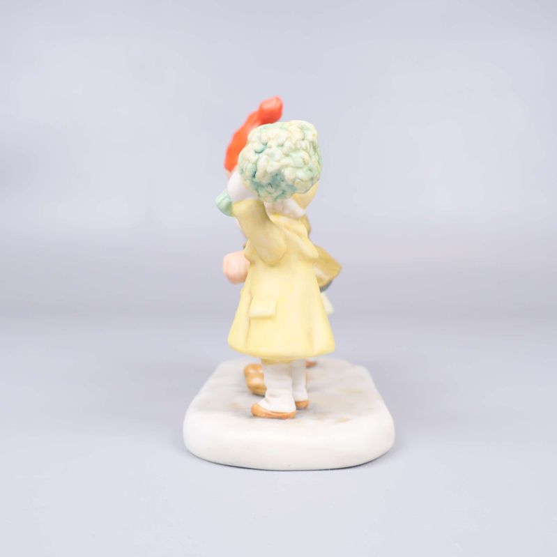 Sida av figur där barnet i gult håller bukett