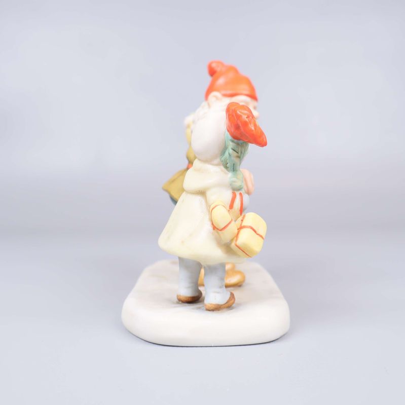 Sida av figur där barnet i vitt håller paket