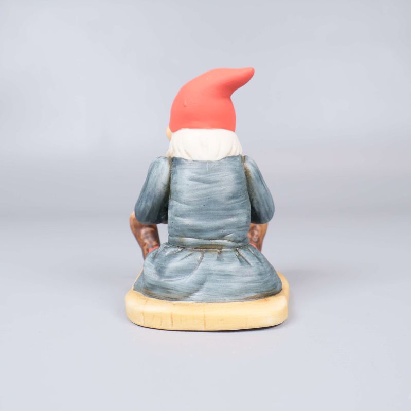 Baksidan av tomtefiguren i blå dräkt och röd luva