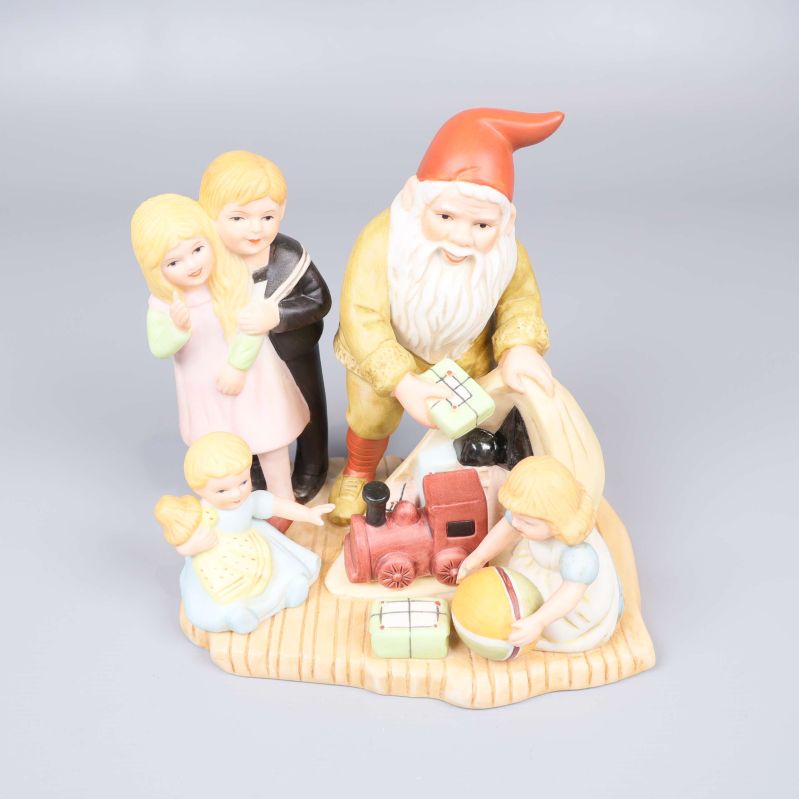 Porslinsfigur med tomte och fyra barn runt presenter