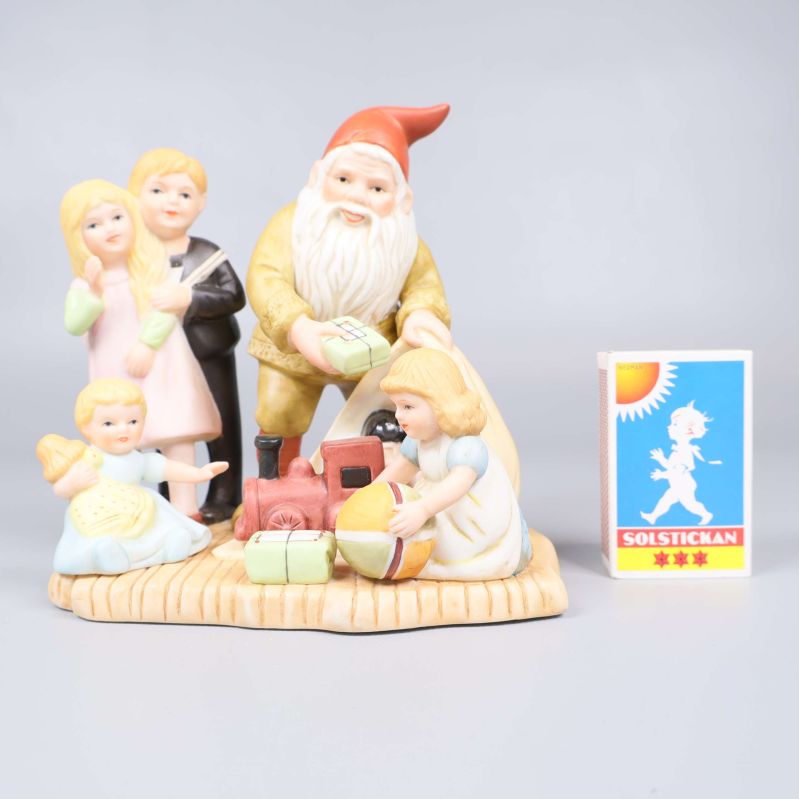 Porslinsfigur tillsammans med tändsticksask för storleksjämförelse