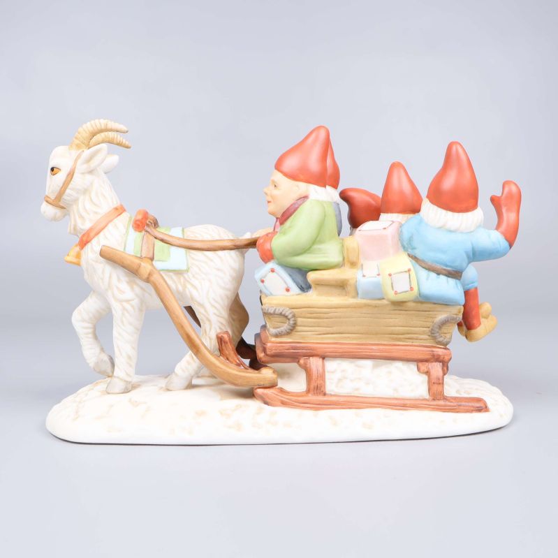 Tomtefigur i porslin sedd från sidan mot tomtarna på släden