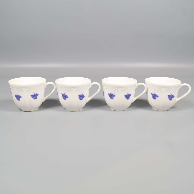 Fyra kaffekoppar i vitt med blå blommotiv på rad