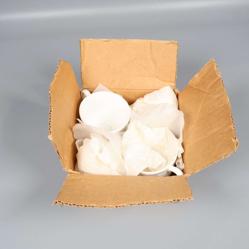 Öppen kartong med packade kaffekoppar och papper