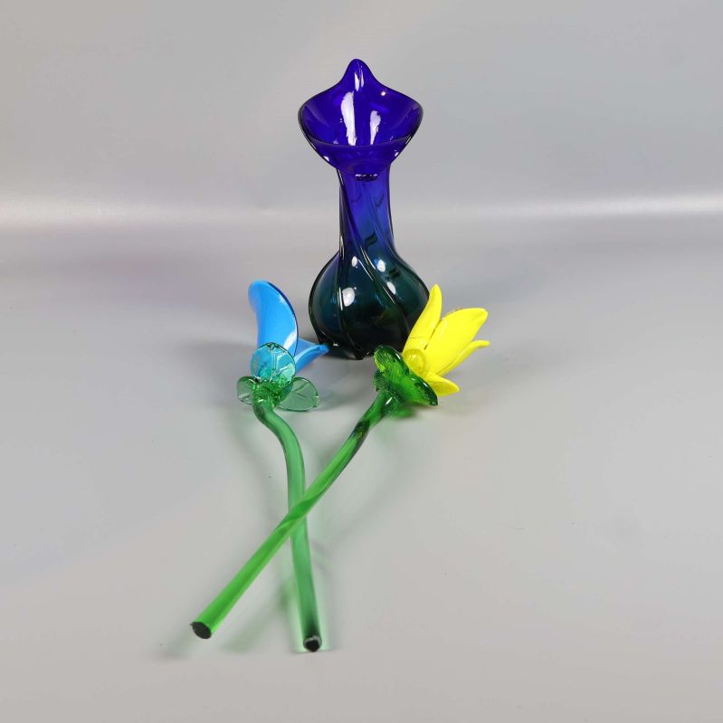 Vas och lösa glasblommor på bordsyta