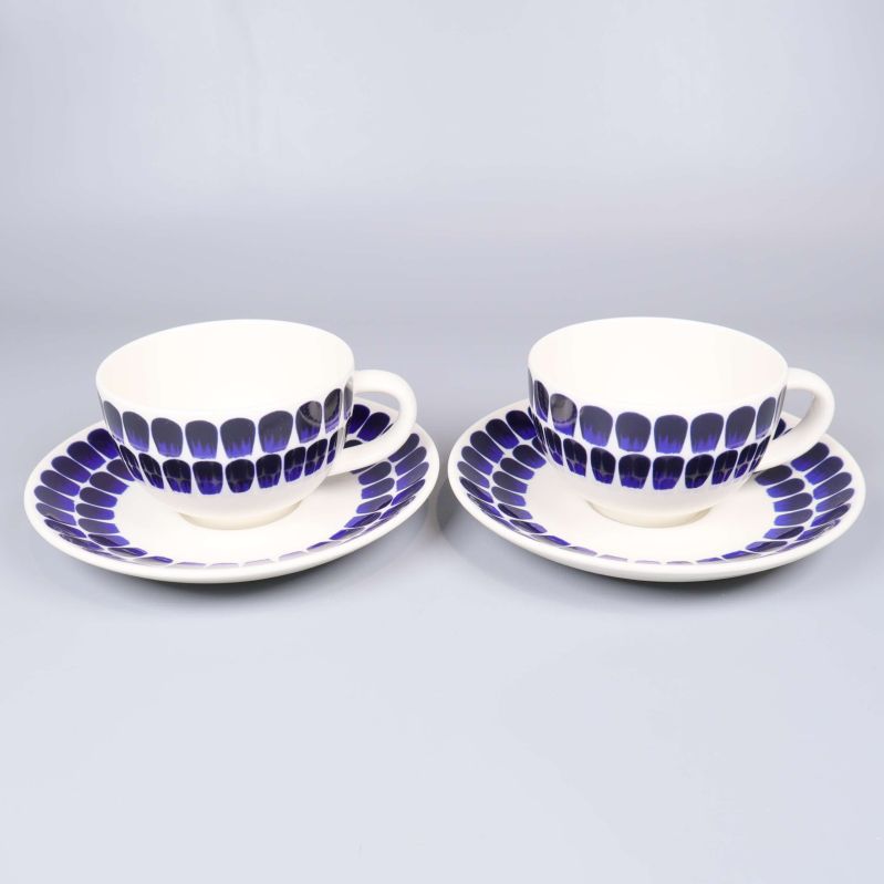 Två vita kaffekoppar med blå dekor och matchande fat
