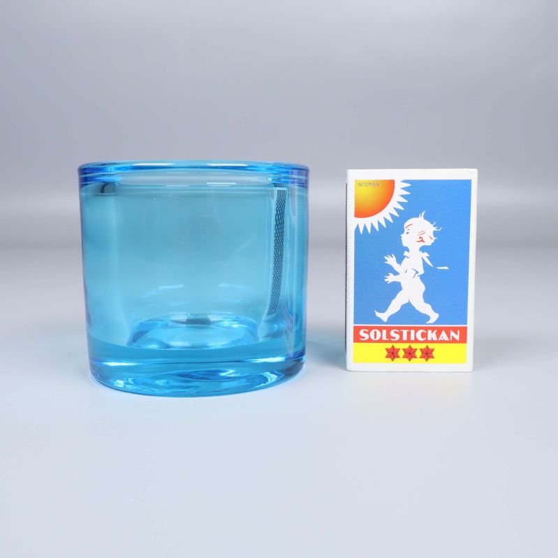 Blå glaslykta bredvid tändsticksask för storleksjämförelse