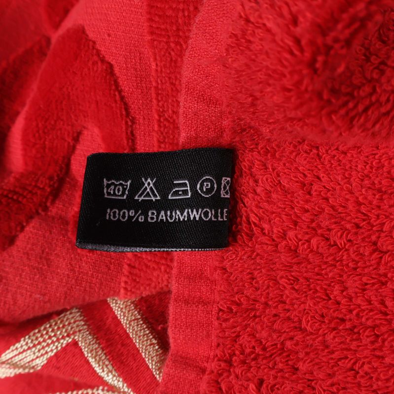 Tvättrådsetikett med text 100% Baumwolle på röd handduk