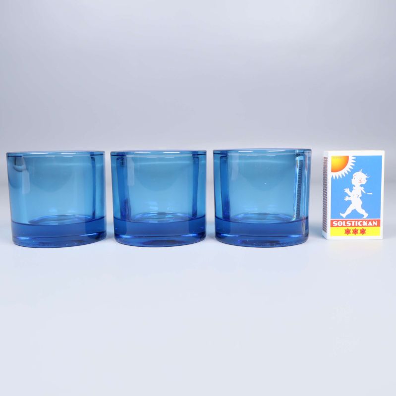 Tre blå ljuslyktor i rad bredvid ett tändsticksask för storleksjämförelse