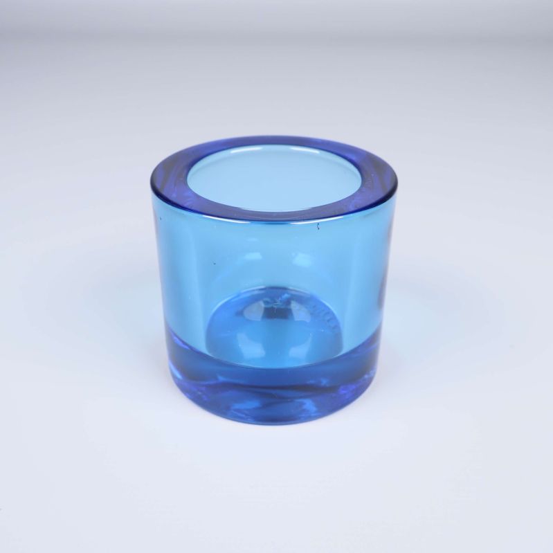 En ensam blå ljuslykta i glas på vit bakgrund