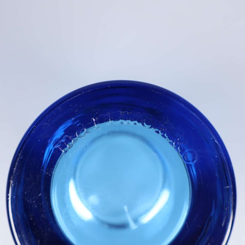 Närbild på botten av blå ljuslykta med gravyr Marimekko