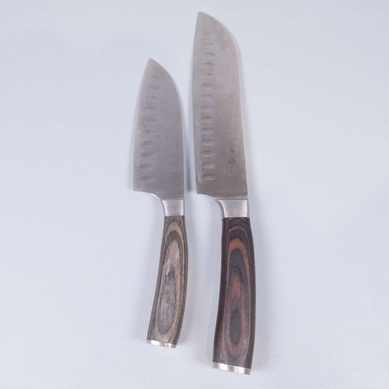 Två japanska knivar med mönstrade trähandtag på vit bakgrund