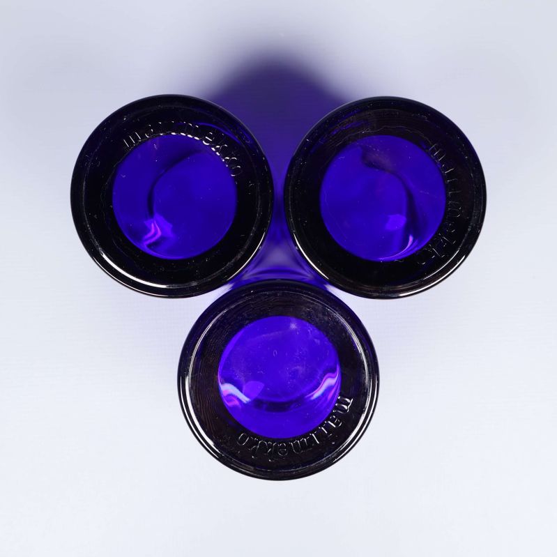 Tre ljuslyktor i blått sedda underifrån mot vit bakgrund