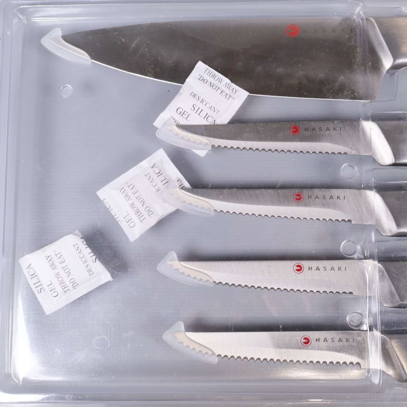 Närbild av blad med Hasaki-logga och etiketter på knivarna