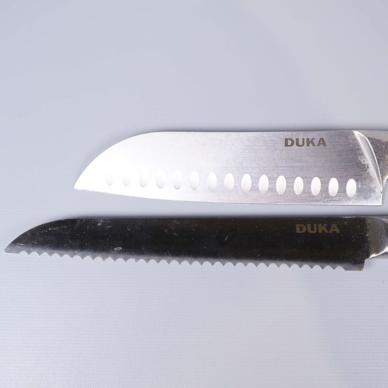 Närbild på två knivar med Duka-logotyp på bladet