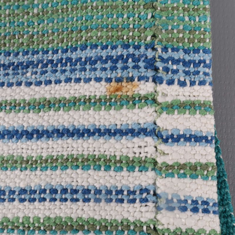 Närbild på tyg med synlig fläck på randig löpare