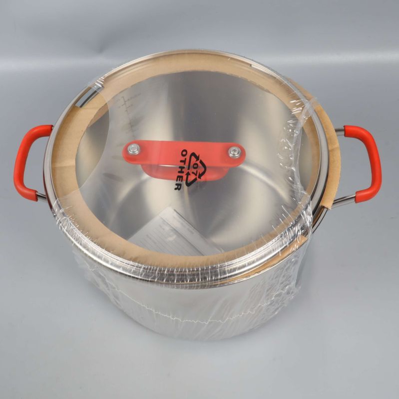 Toppen av rostfri gryta med glaslock och röda handtag
